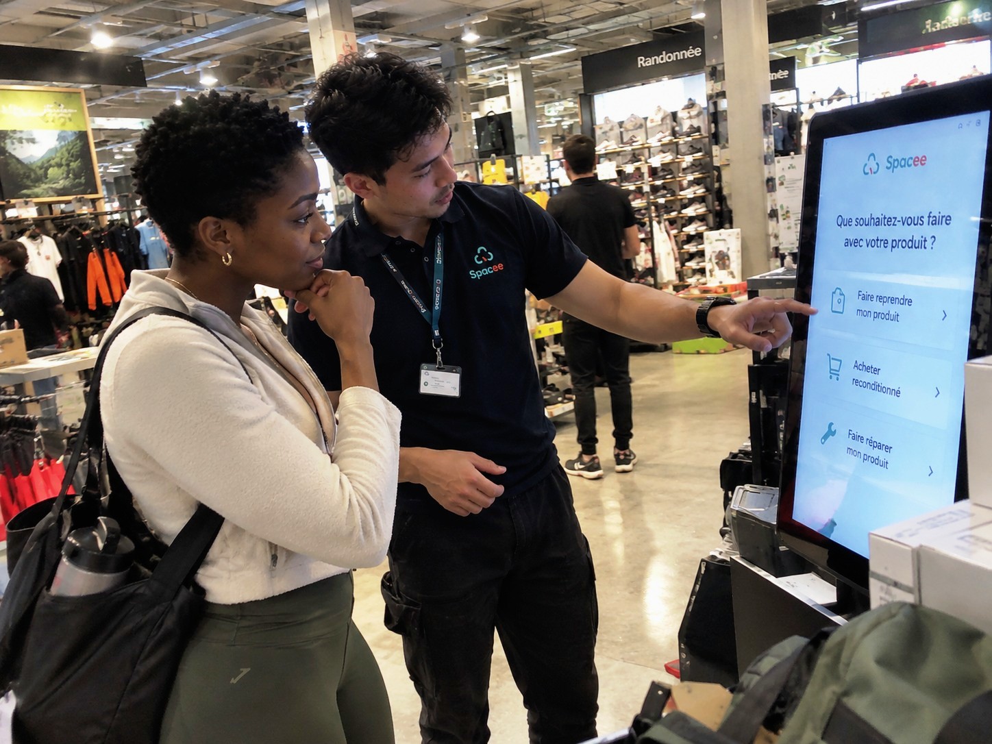 Conseiller et cliente devant une borne en magasin